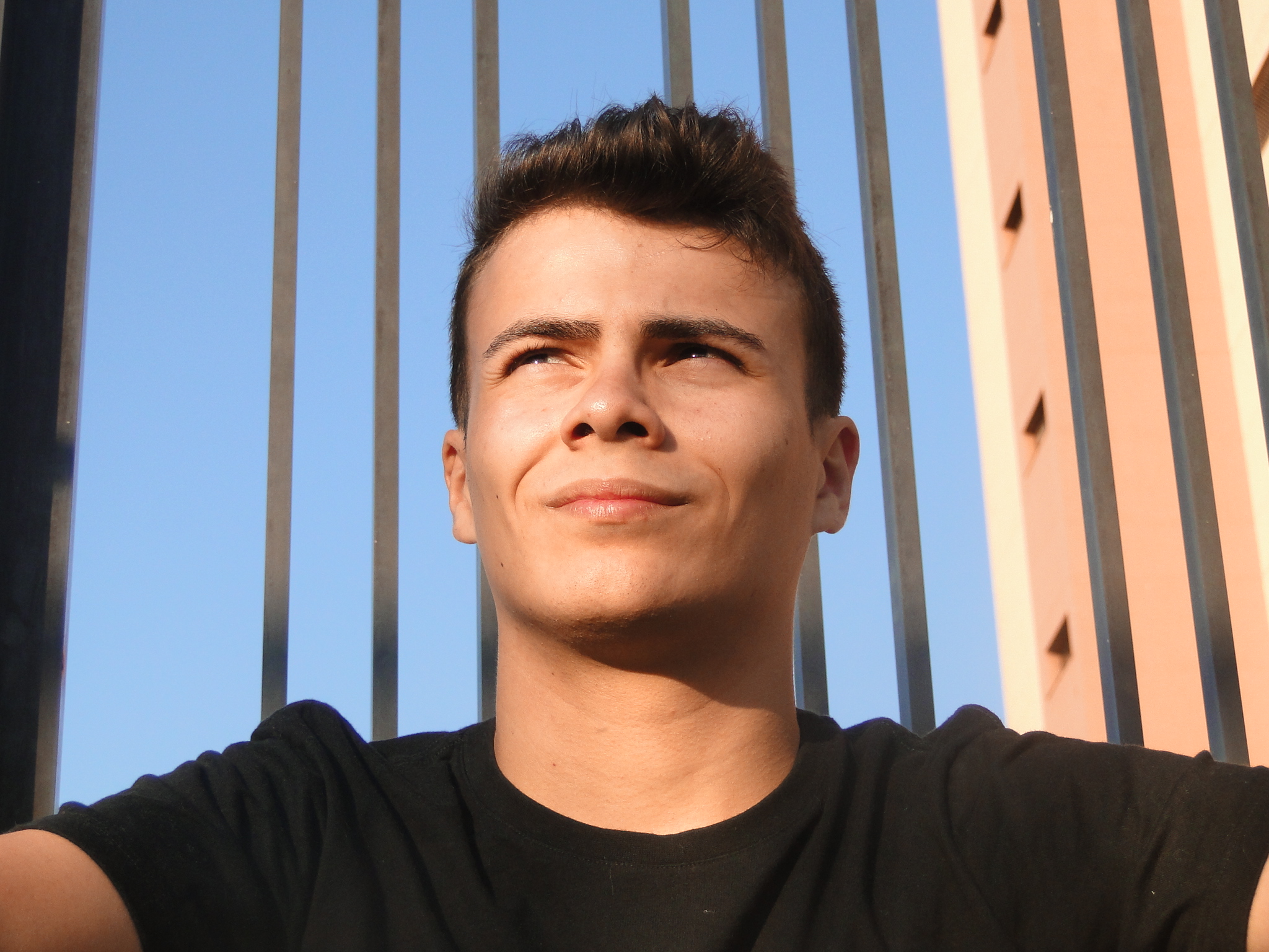 Foto de Luís Otávio Gaido Grizzo, na foto ele usa uma camisa preta e olha para o horizonte com o sol no rosto.